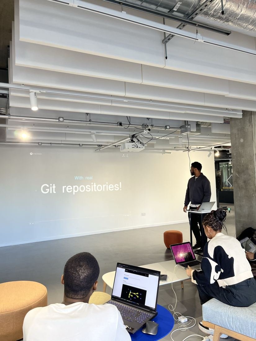 A workshop in progress, with a slide reading 'Git repositories!' and students following along on laptops.