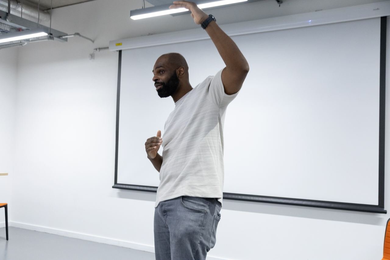 A speaker gestures towards the screen while presenting.